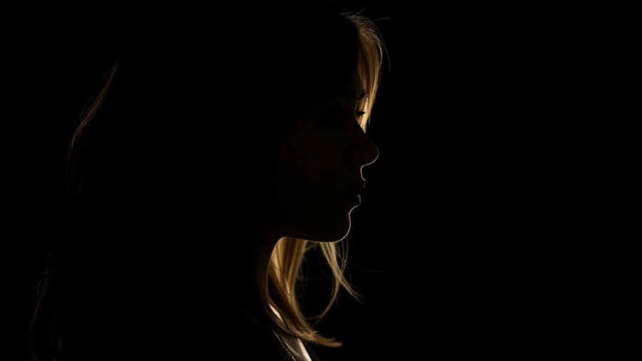 Silhouetted woman lost in thought suggesting habits that drain inner peace and happiness.