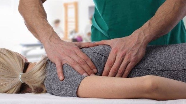 chiropractor adjusting female patient's back