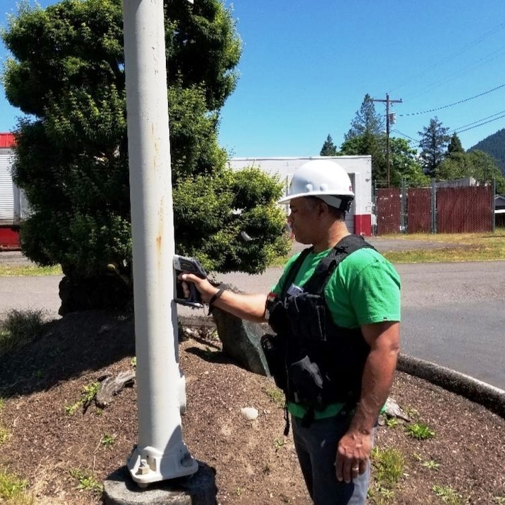 Man in a hard-hat checking for lead paint on a street sign