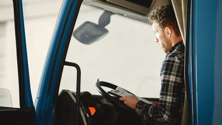 Truck driver in red shirt reflecting on English proficiency rules.