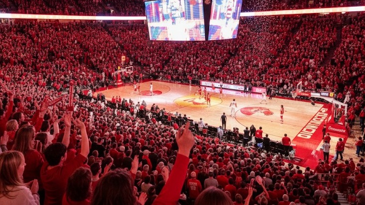 Energetic Arkansas basketball event with a lively crowd and speaker.
