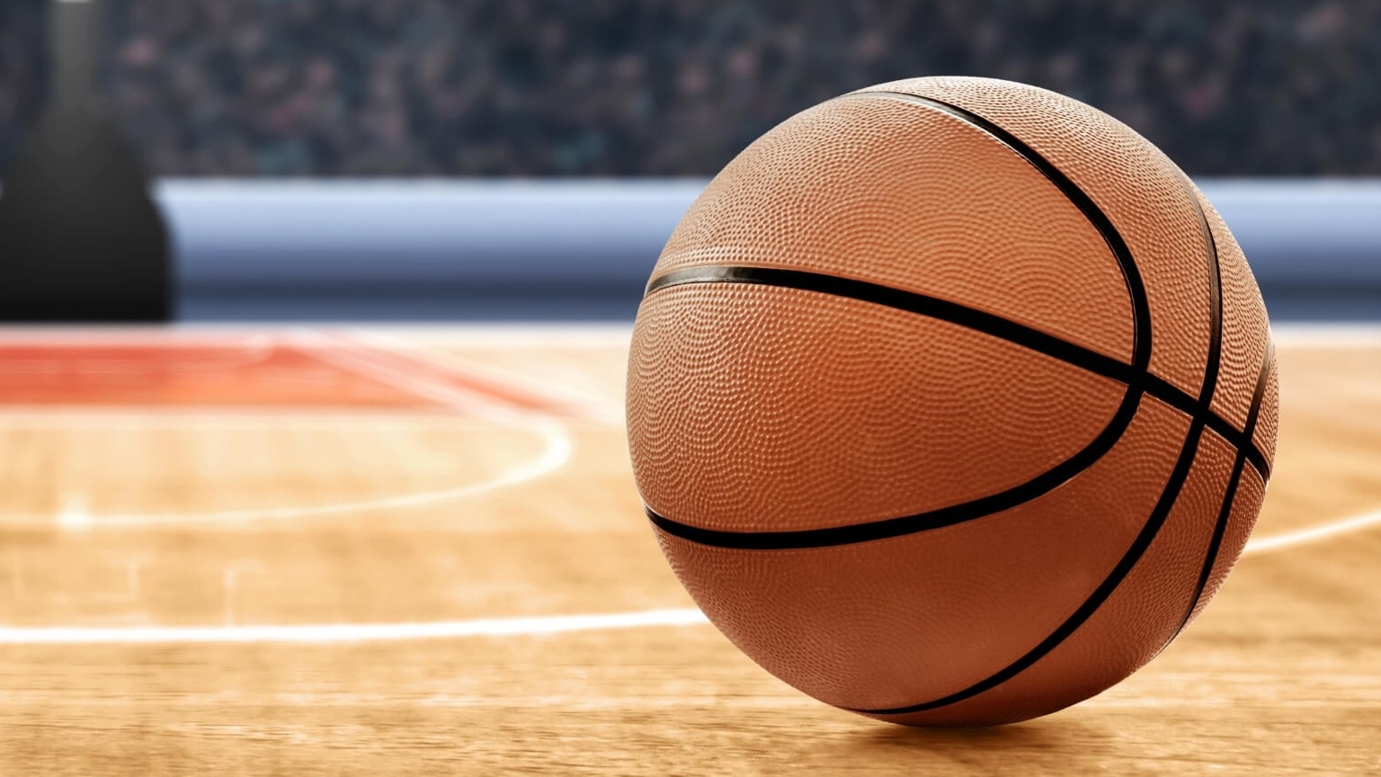 Basketball player celebrating on court in vibrant stadium lighting.
