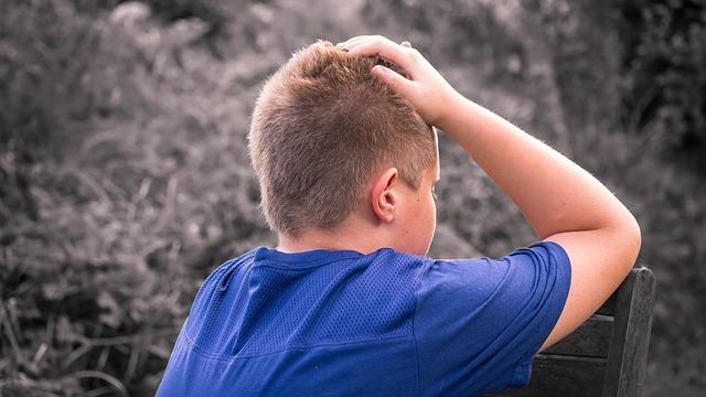 Back of boy looking over chair outdoors