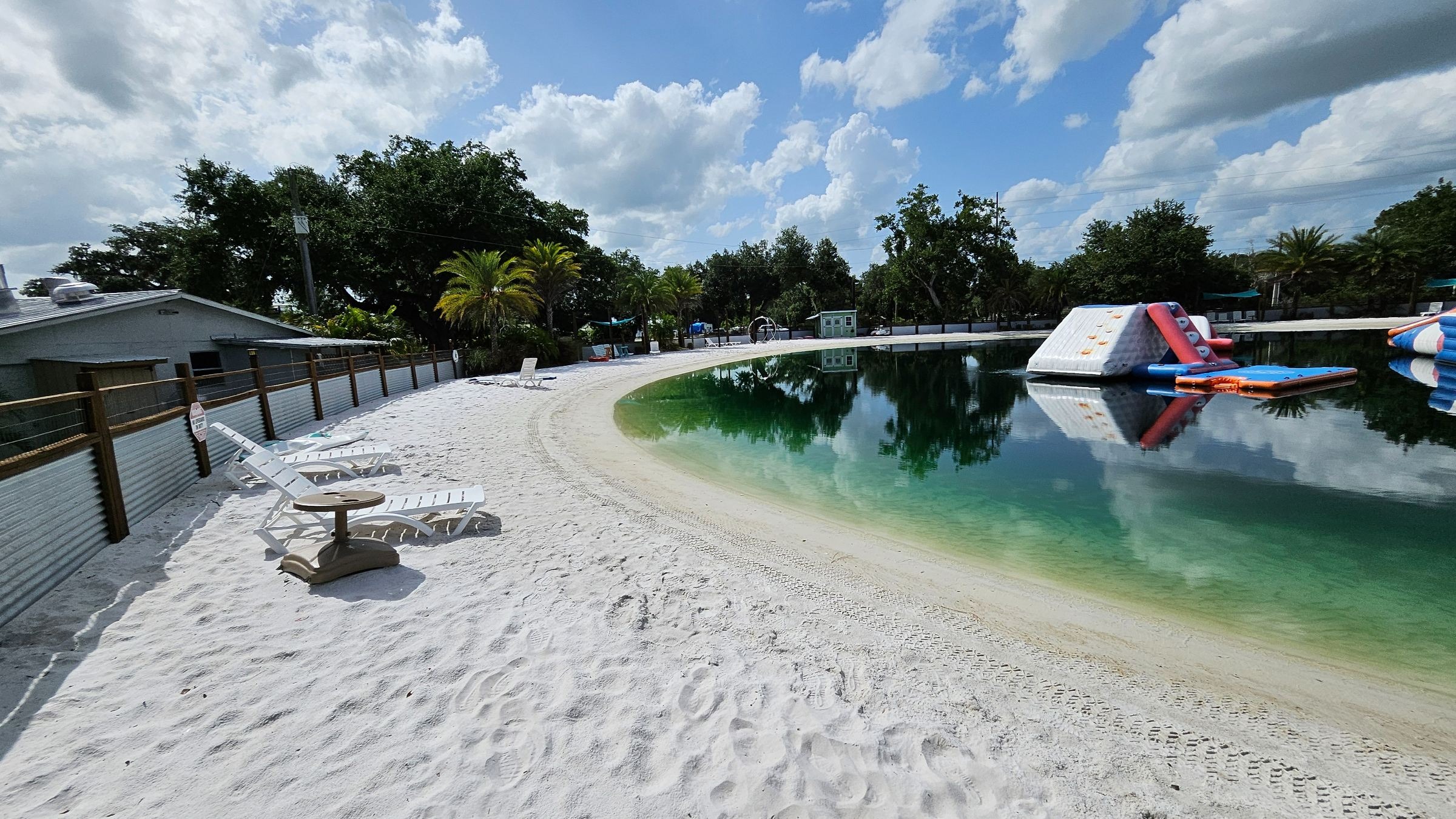 Aerial view of Christian camp in Central Florida surrounded by lush greenery, tranquil lake, inviting walking trails, birds flying, bright morning light