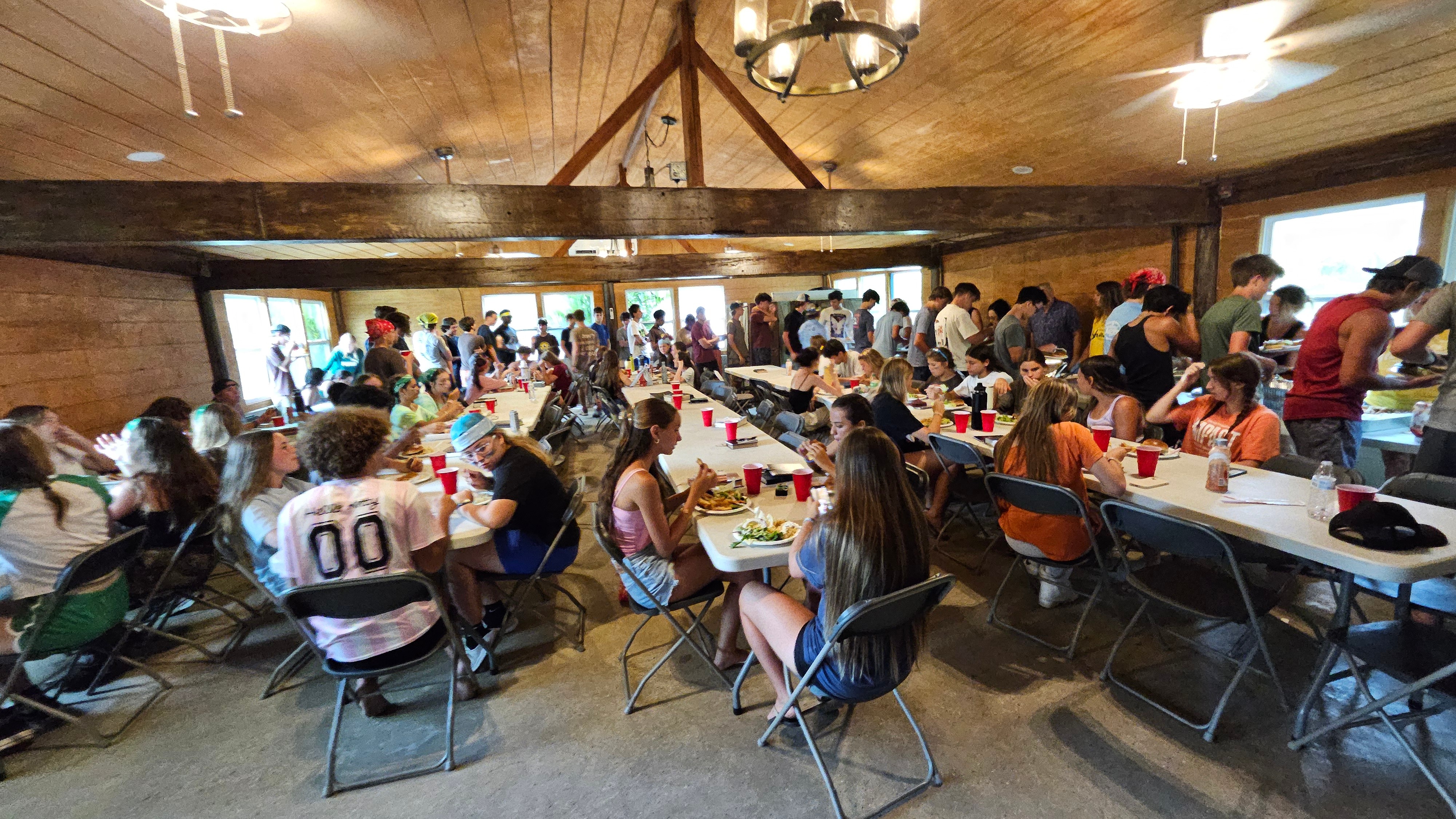 group of adults in an outdoor planning meeting at christian camp in central florida, collaborative, using brochures, cabins and picnic table, pine woods