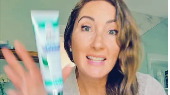 Cheerful woman demonstrating toothpaste in bathroom – What's in your toothpaste.