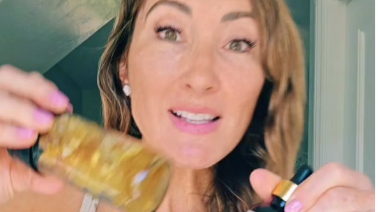 Woman displaying frankincense essential oil bottles indoors.