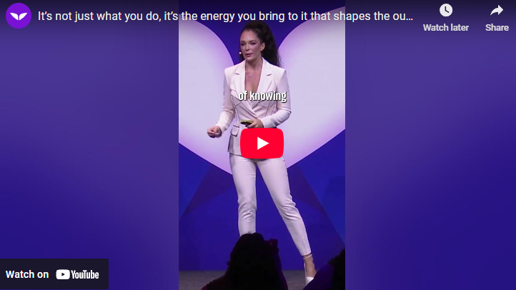 Confident speaker presenting on stage with purple background, energy affects outcomes.