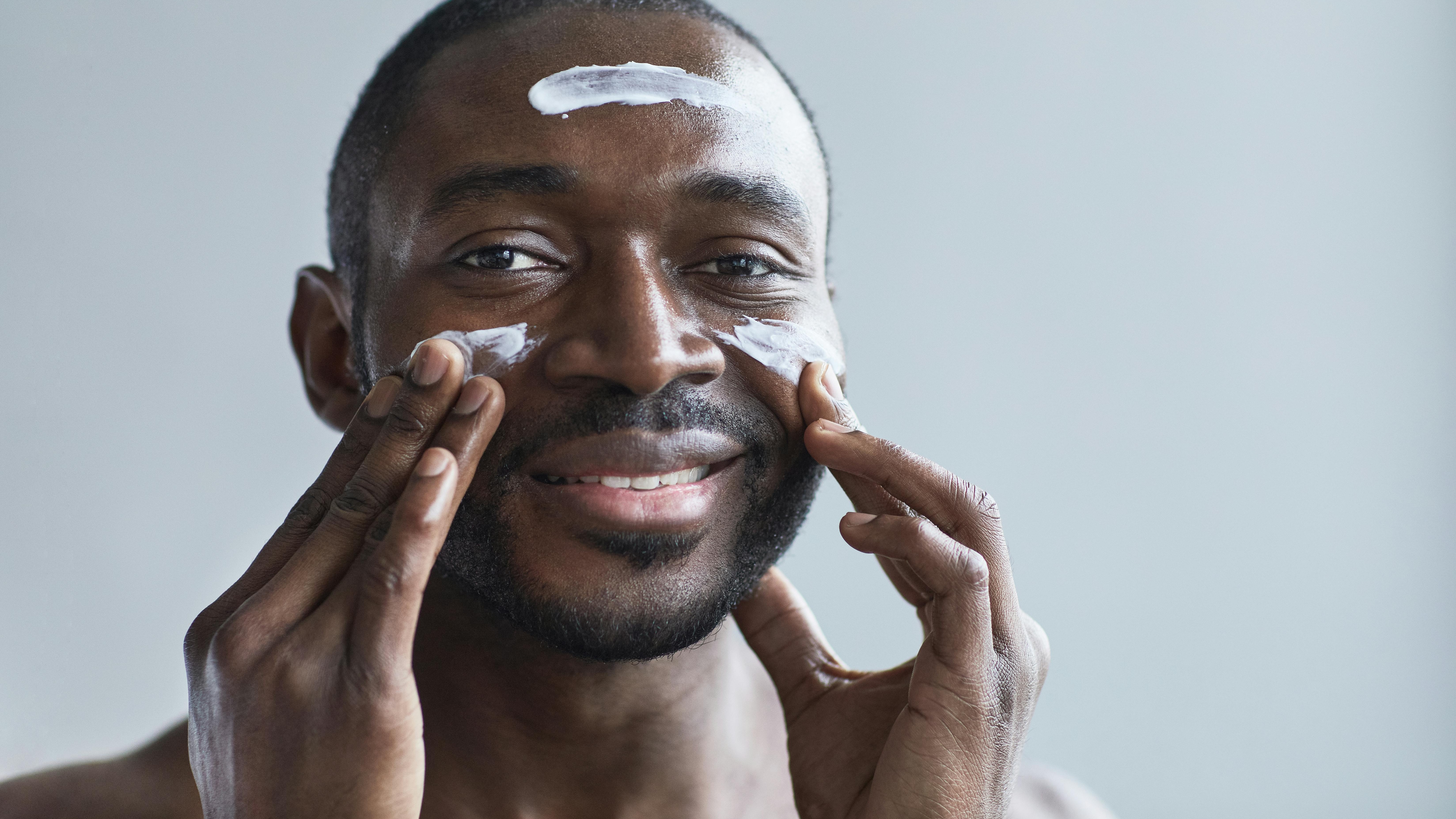 Man applying moisturizer with hands, showcasing men's skincare tips for all skin types.