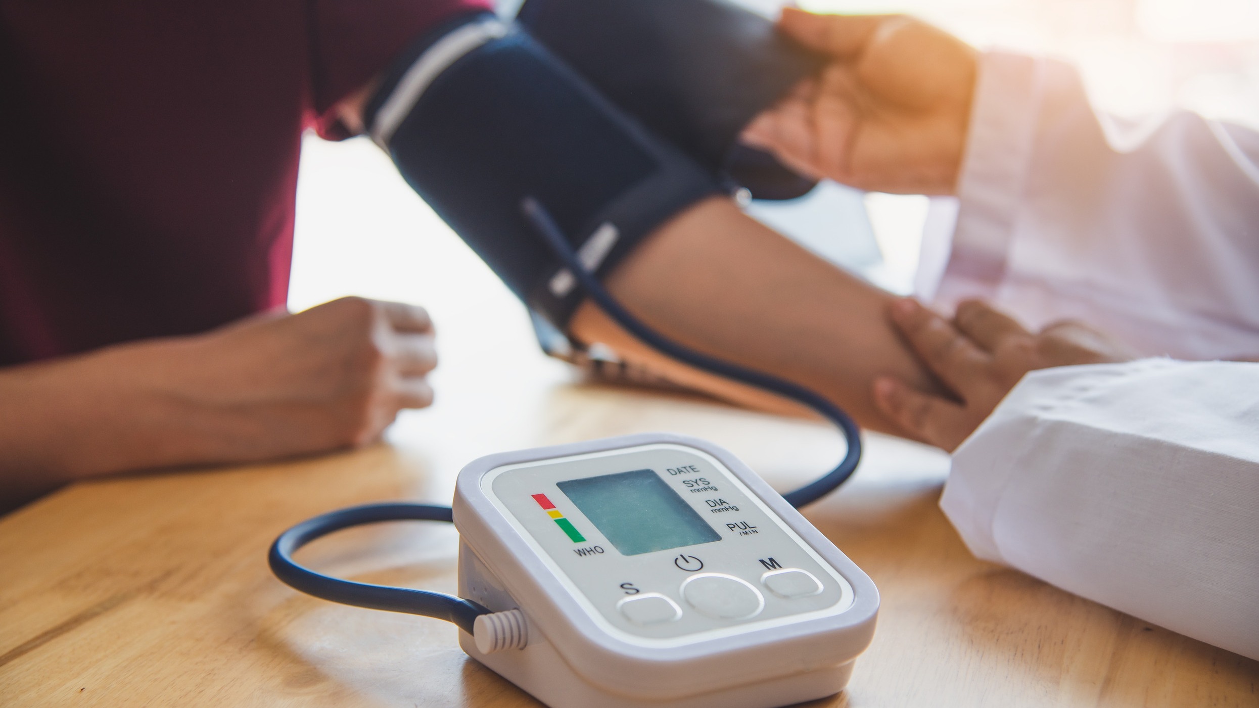 doctor measuring blood pressure for cardiovascular health management in a medical office.