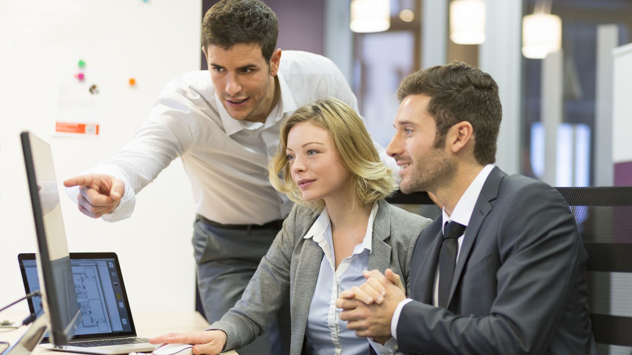 three co workers looking at monitor