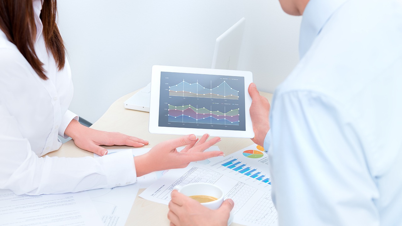 male and female business people looking at line graph on tablet