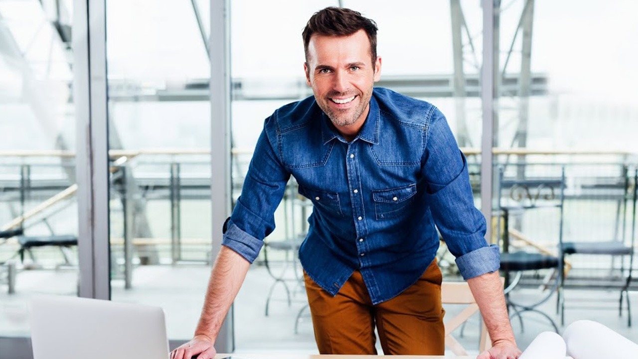 young male blue shirt hands on desk smiling