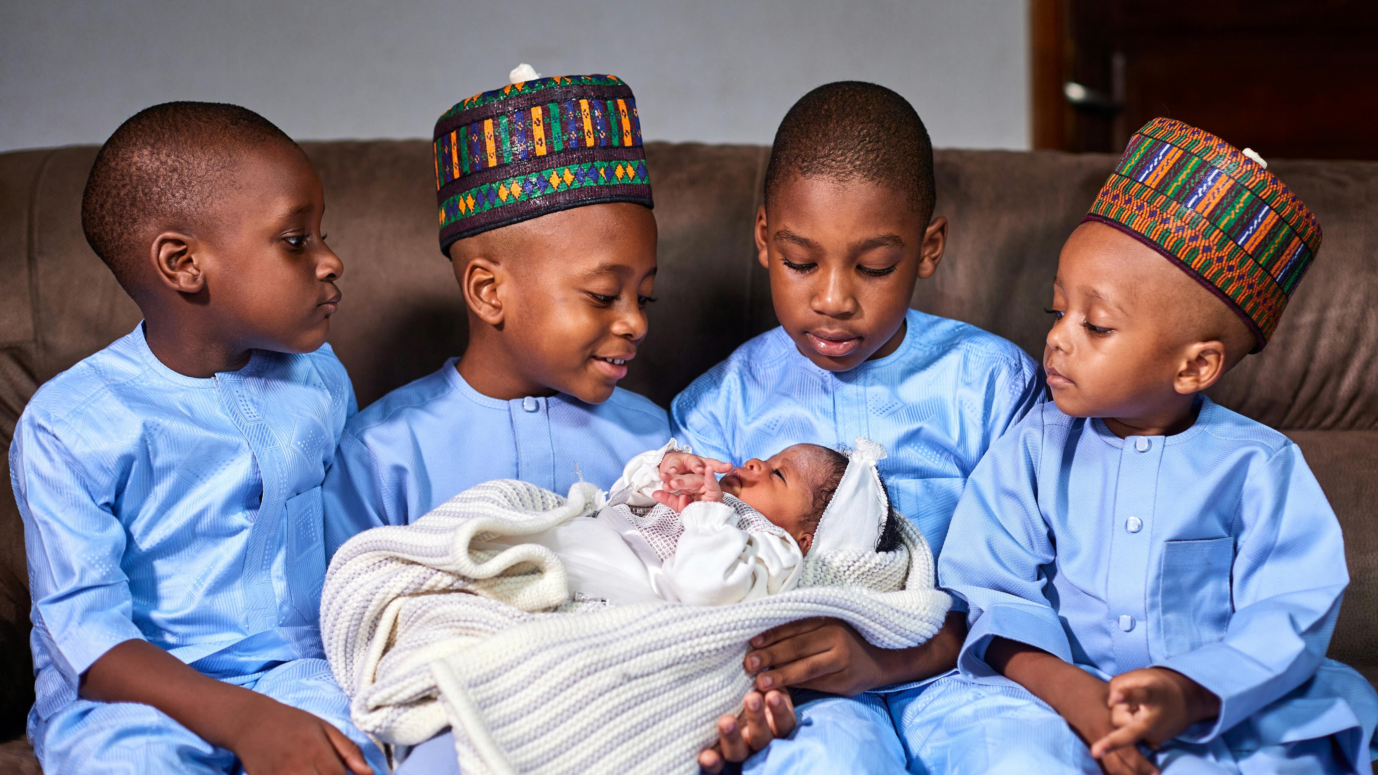 Warm-hearted Ugandan family smiling; parents lovingly holding a small child in a traditional Kampala neighborhood; child health Uganda, pediatric care Kampala