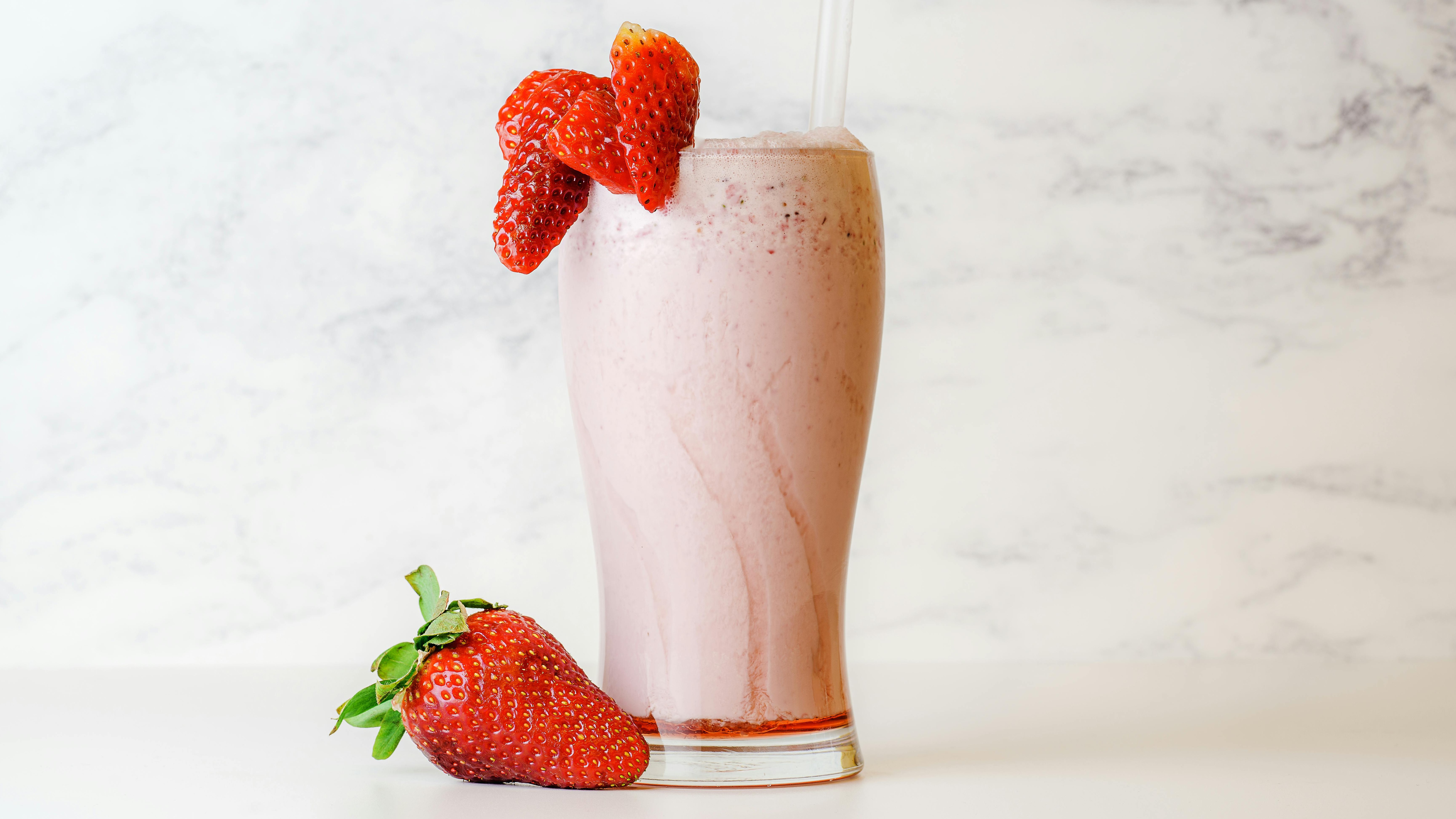 Variety of milkshakes being poured into MilkShake Factory cups.
