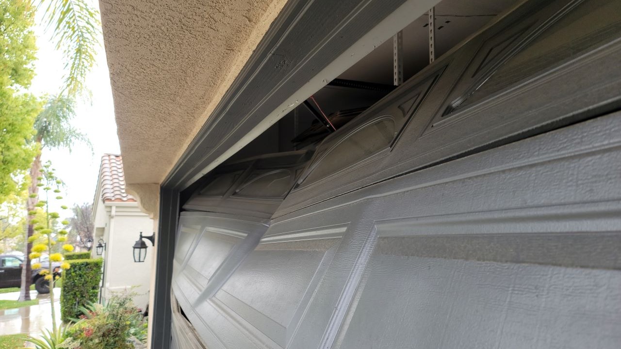 Damaged Garage Door due to broken spring and also badly adjusted garage door opener