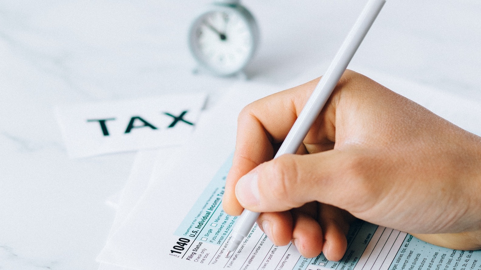 Camdem Tax services: Close-up of tax preparer hand and pen filling out 1040 tax form