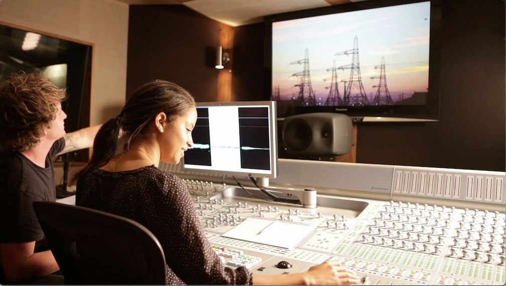 video production team members reviewing footage on a large monitor in an editing room