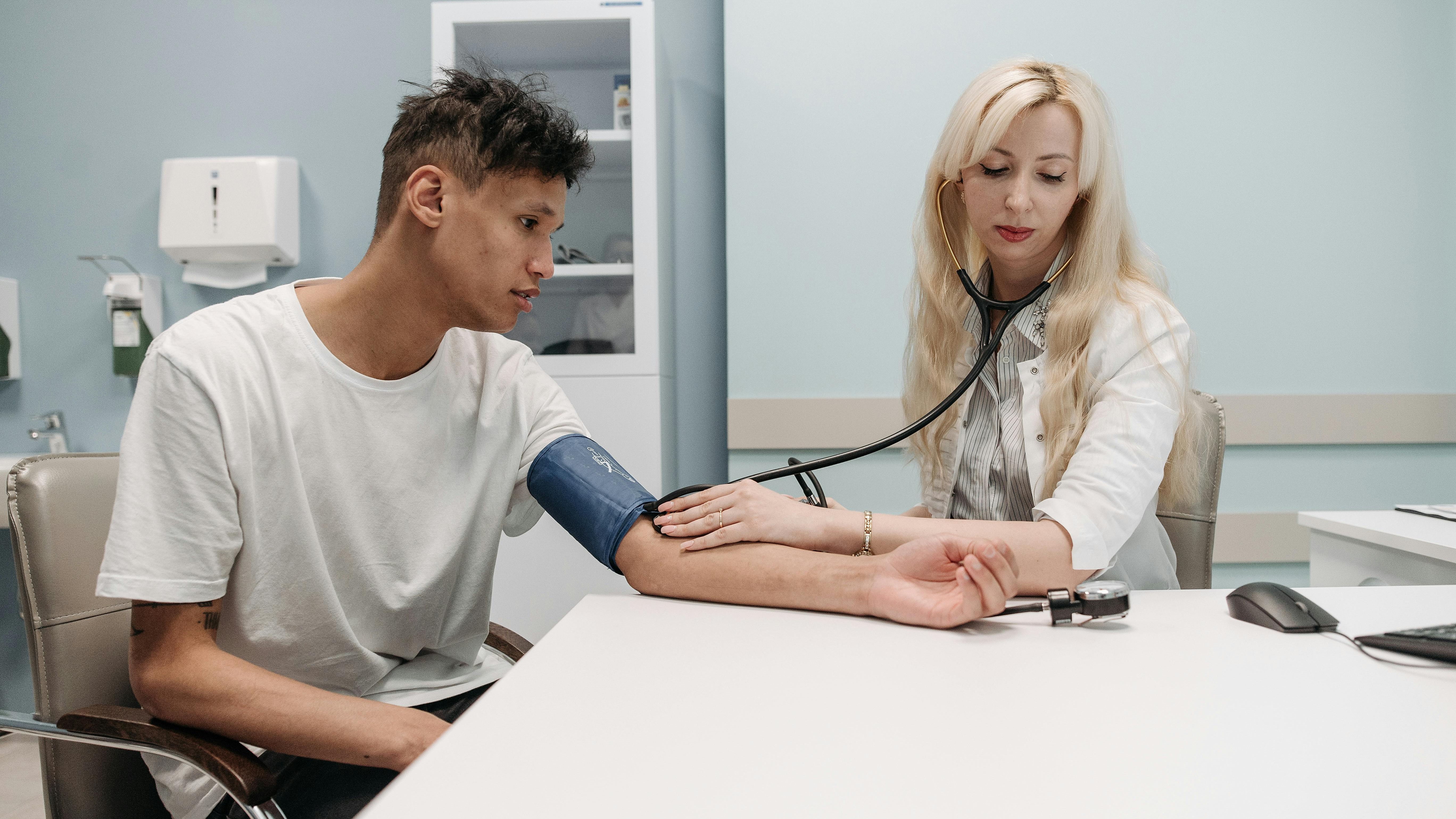nurse reads gauge of BP monitor on Asian male patient