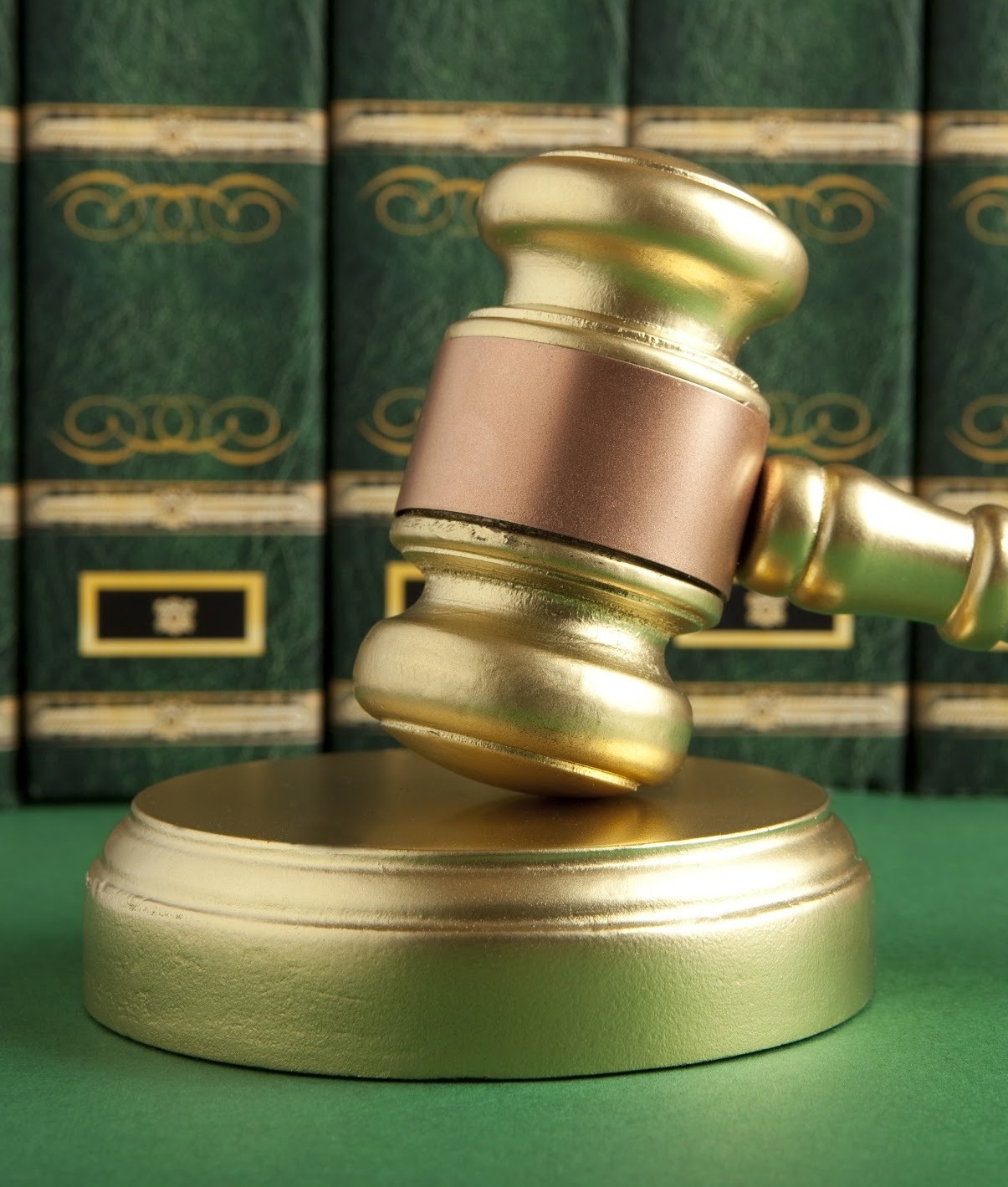 Golden gavel in front of green law books