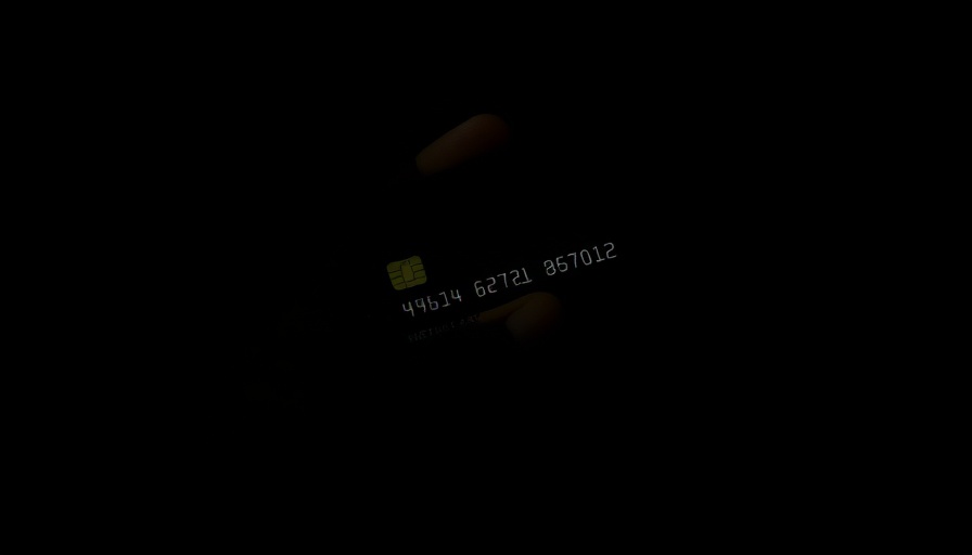 Moody shadowed hand holding credit card, symbolizing credit card debt consequences.