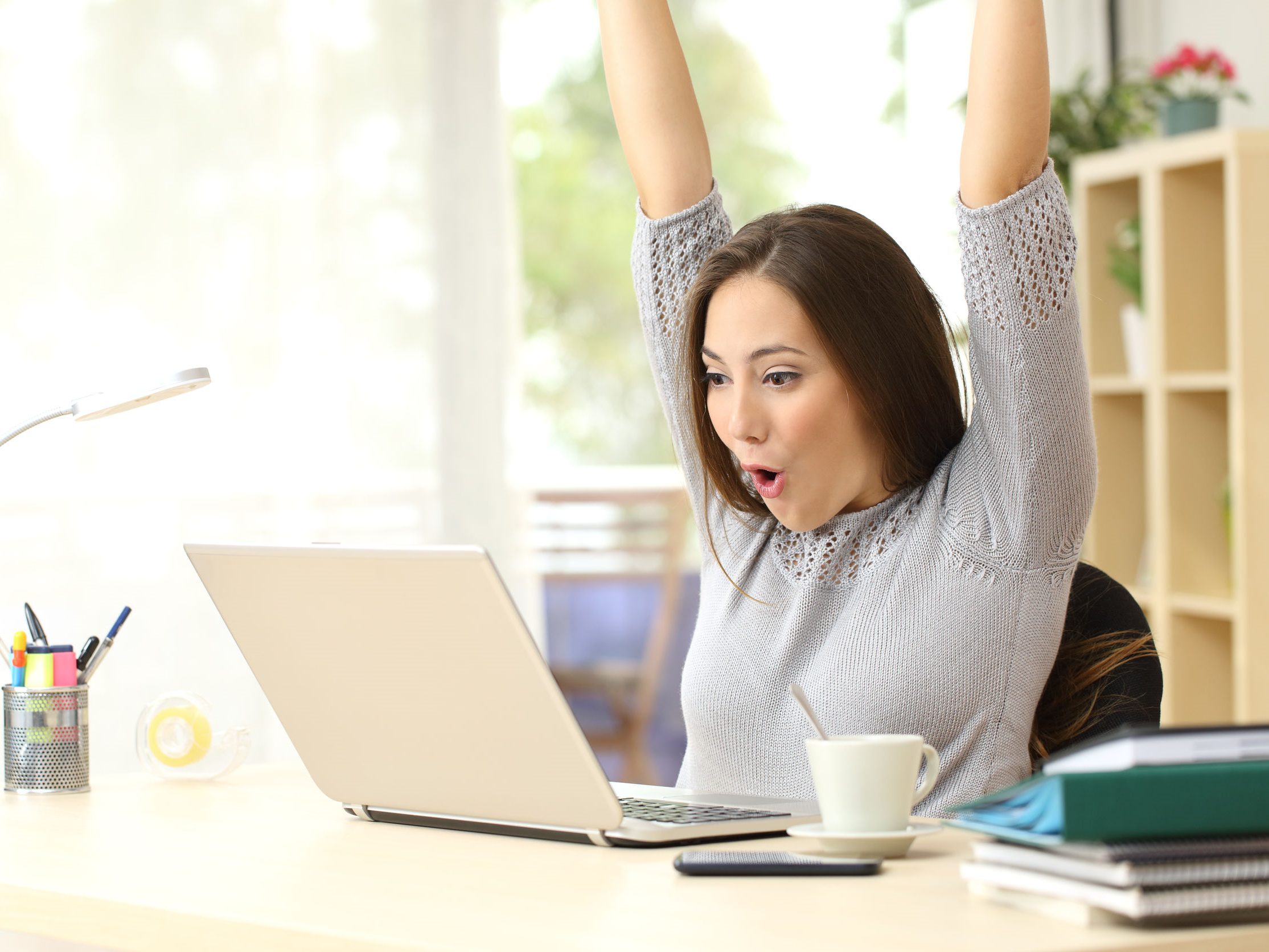 Photo of a Social Response Marketer looking at her laptop waving her arms in the air excited about video marketing
