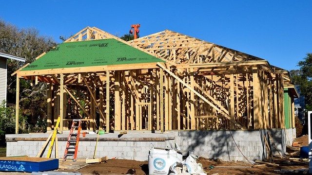 Construction crews install solar panels on sustainable housing development homes.