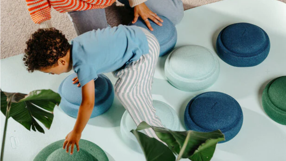 Child playing on colorful cushions in bright living room, Stapelstein Dark Green.
