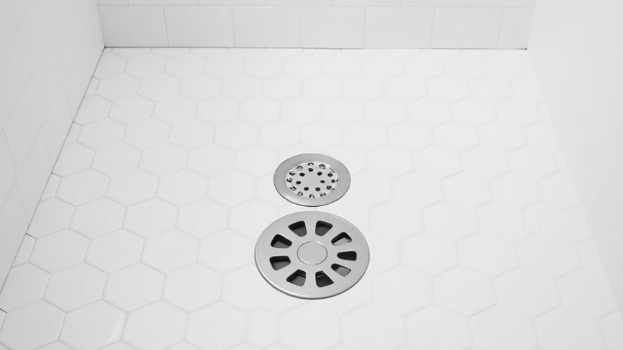 Clean shower drain on white hexagonal tile floor, how to clean shower drain.