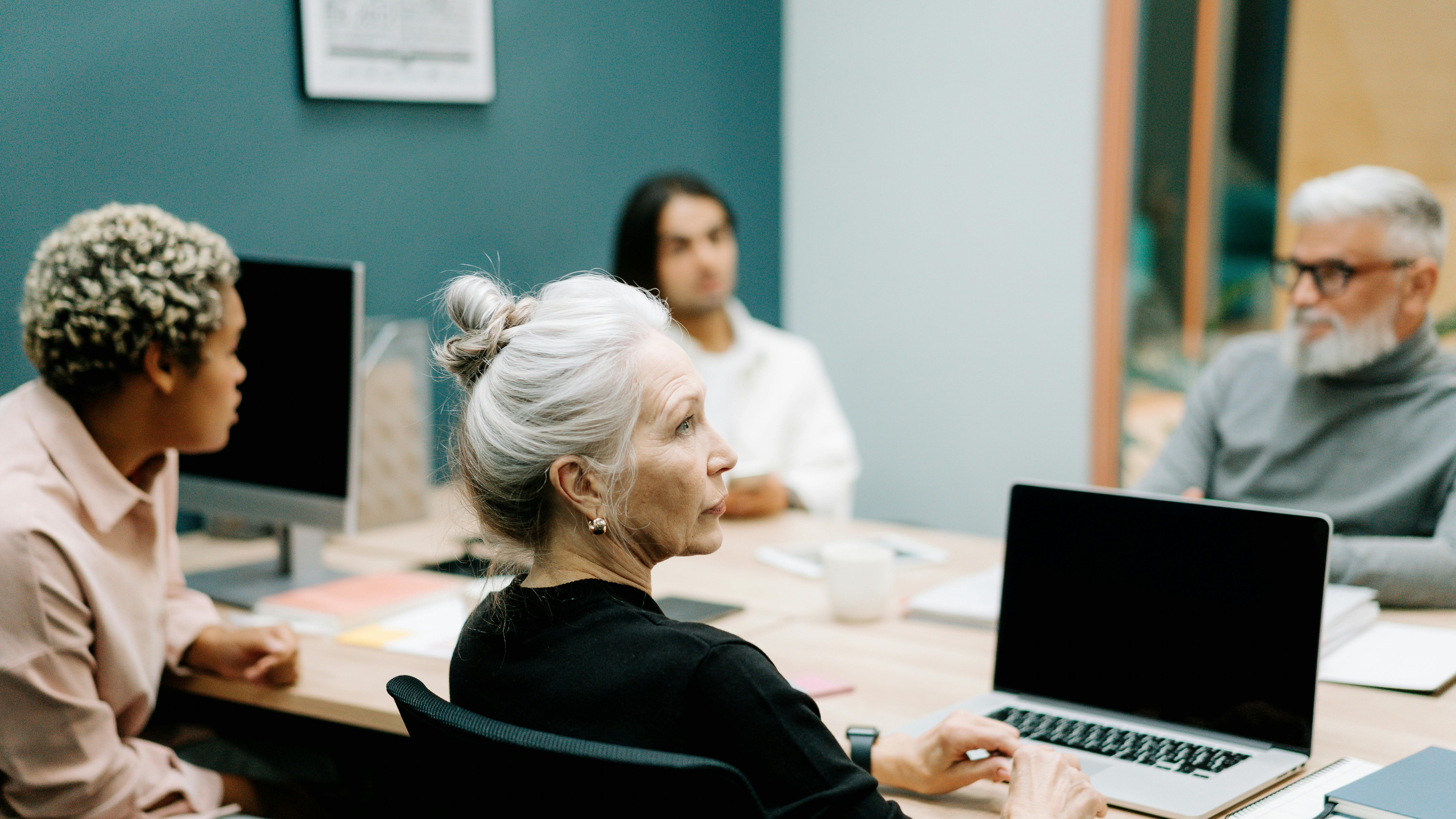 Business professionals discussing CEO compensation and company performance in a bright office.