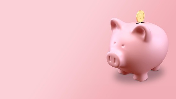 Close-up of hand placing coin in piggy bank, symbolizing Roth catch-up contributions in 401(k) plans.