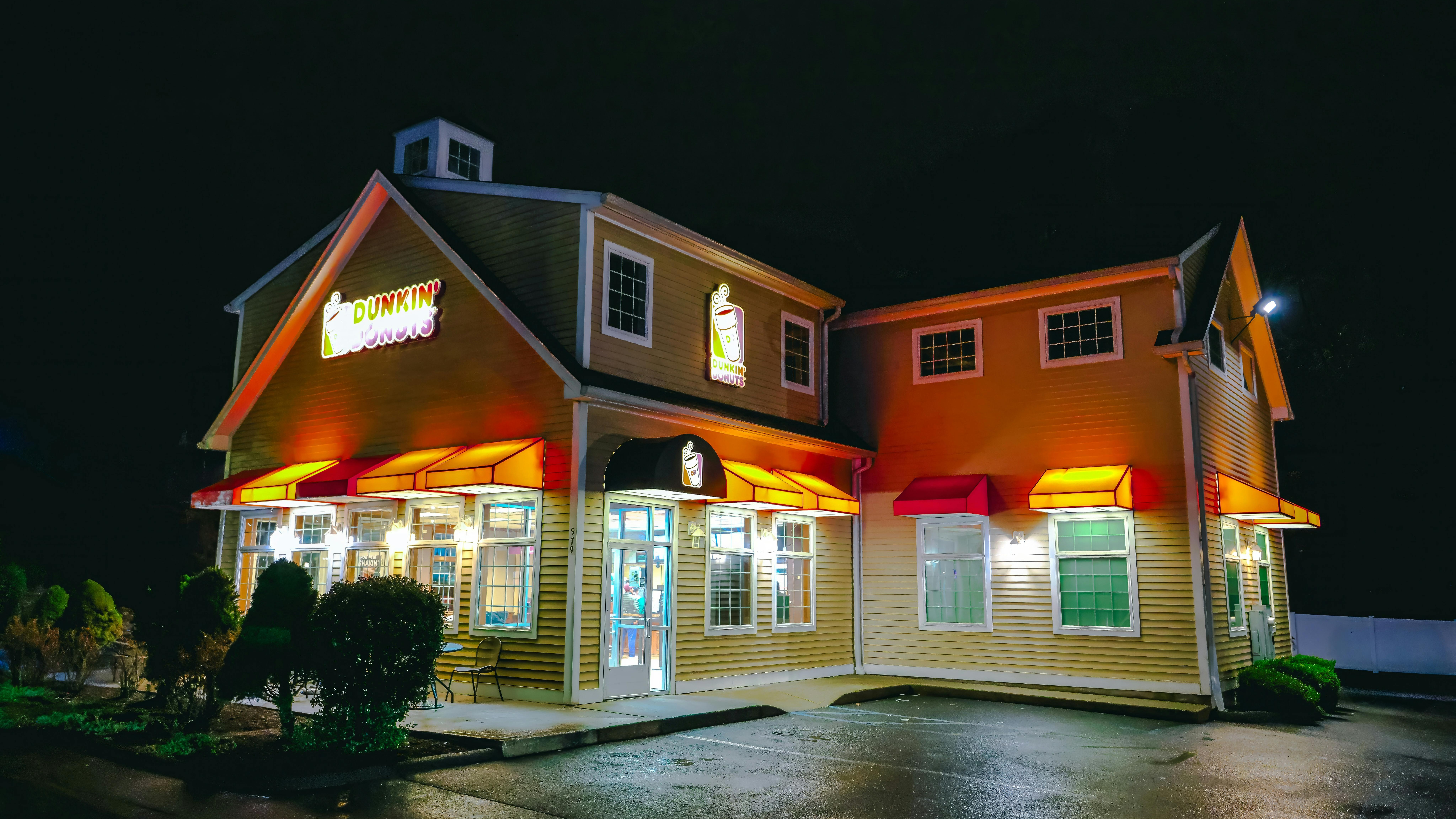 Dunkin' storefront with promotional signs and passerby.