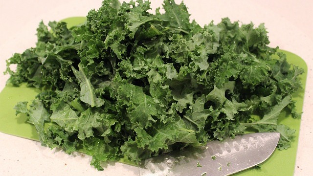 Fresh kale pesto in a jar surrounded by greens, ideal for healthy family meals.