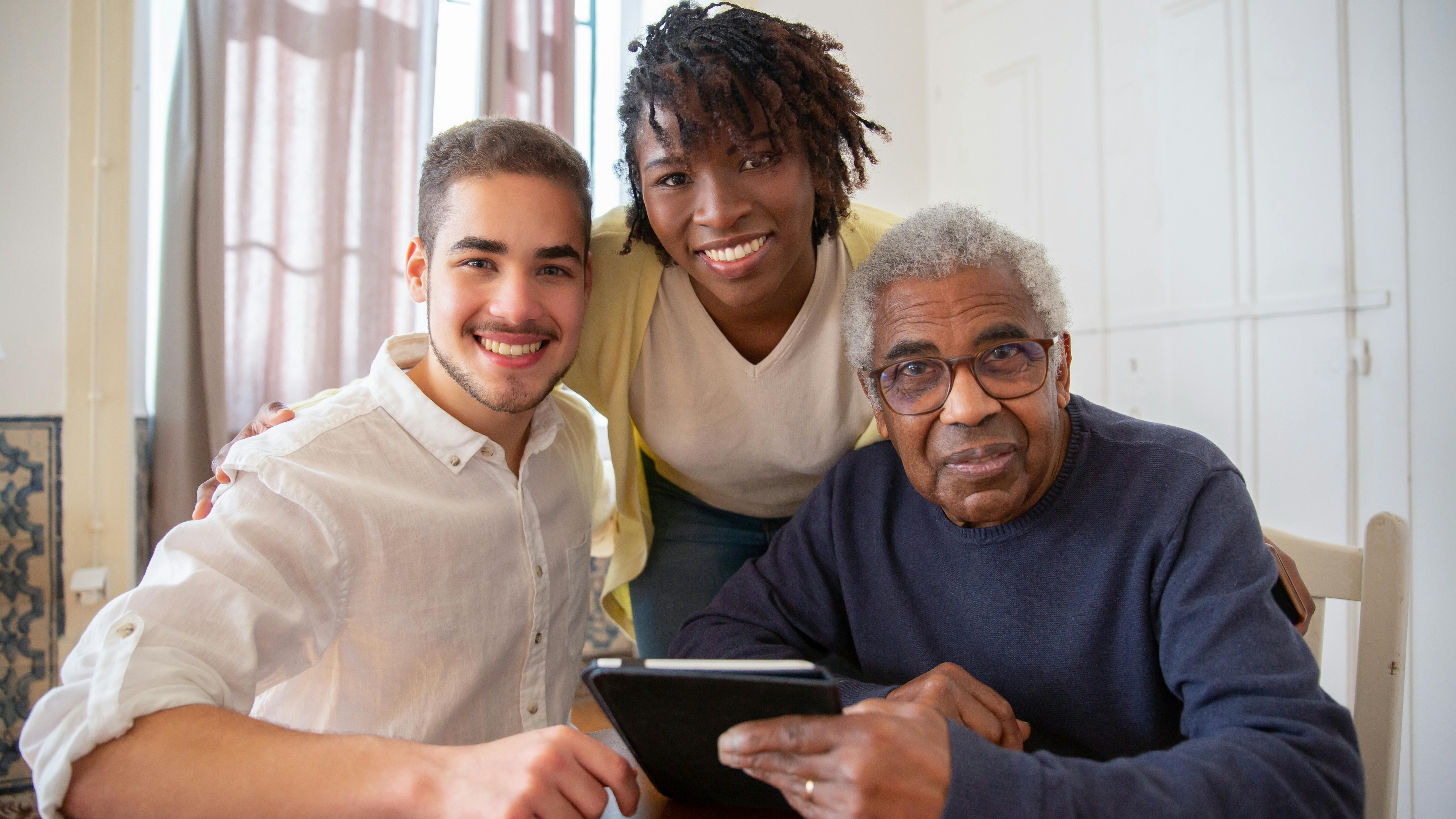 Smiling young caregiver embracing elderly woman indoors for employer branding.