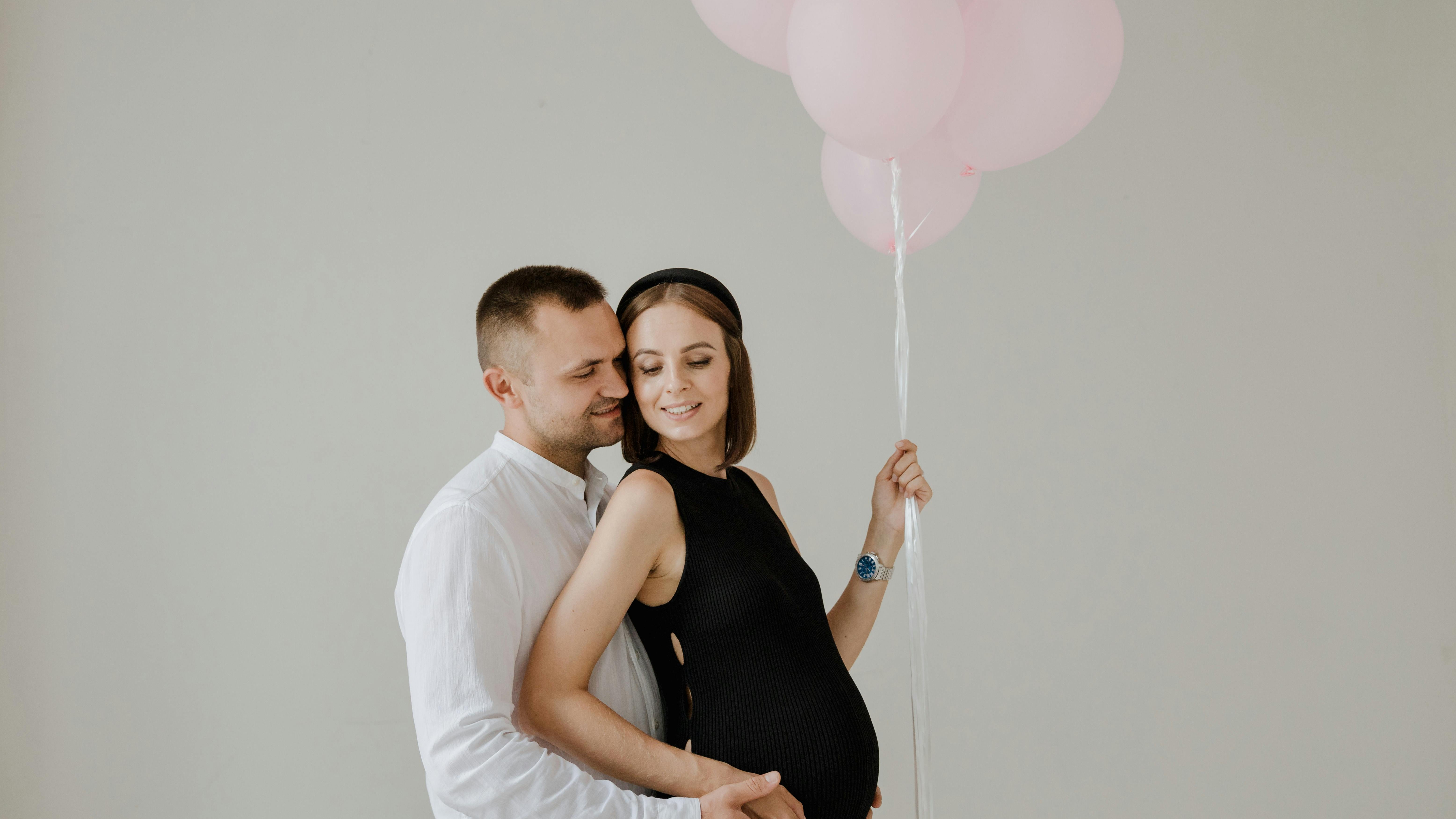 Gender reveal cake held by couple, pastel decor.