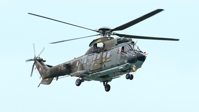 Military Black Hawk helicopter flies with drones at sunset