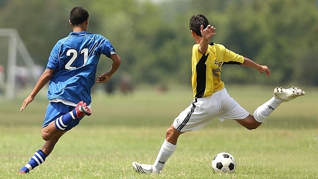 Teen soccer referee job: smiling teen referee holding red card on field.