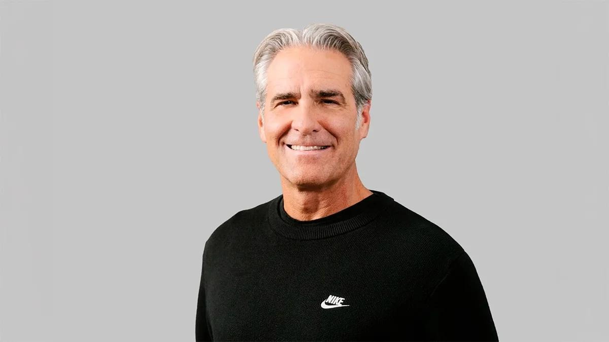 Smiling mature man, black sweater, gray background.