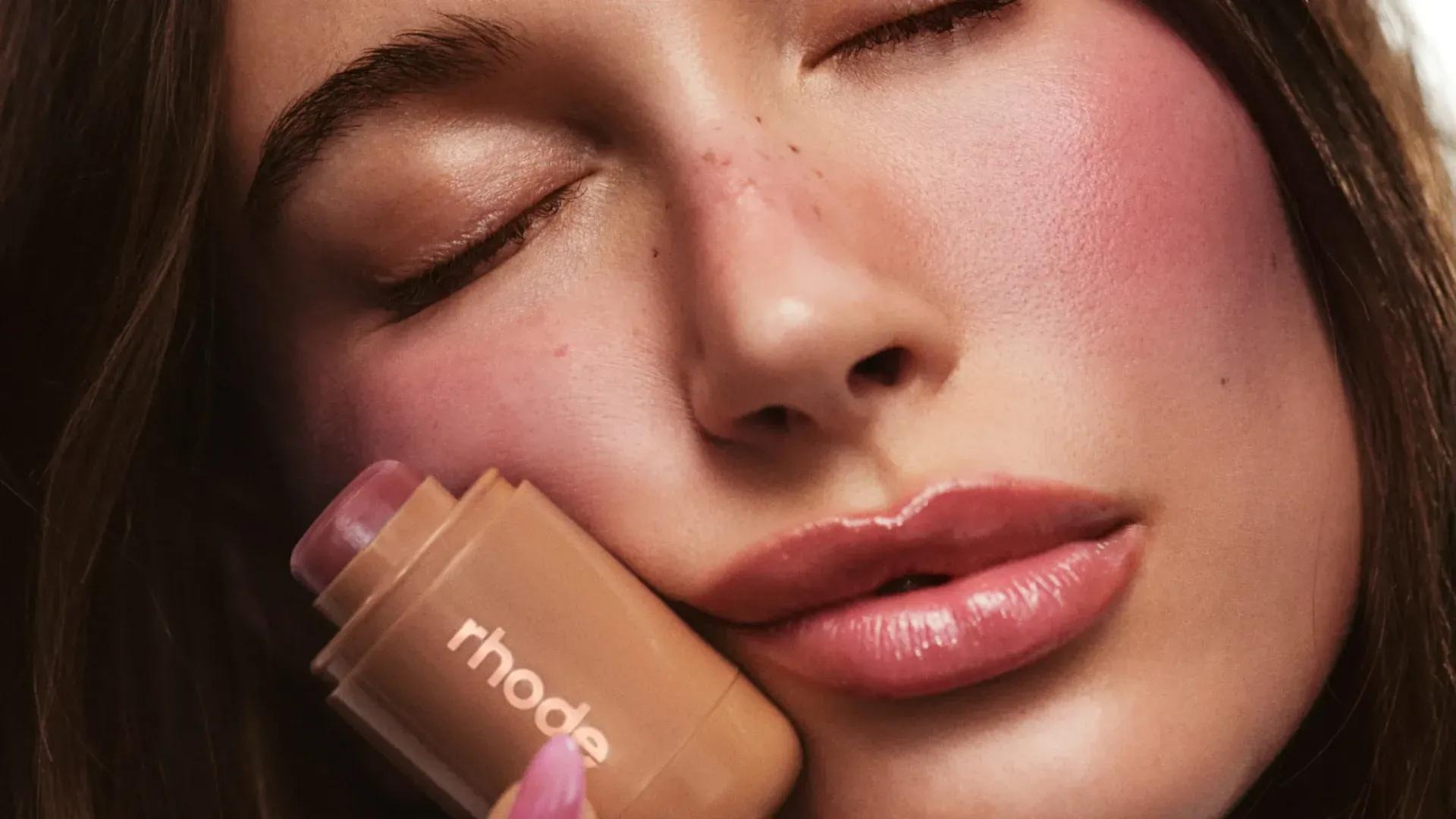 Young woman with glossy complexion promotes skincare product.