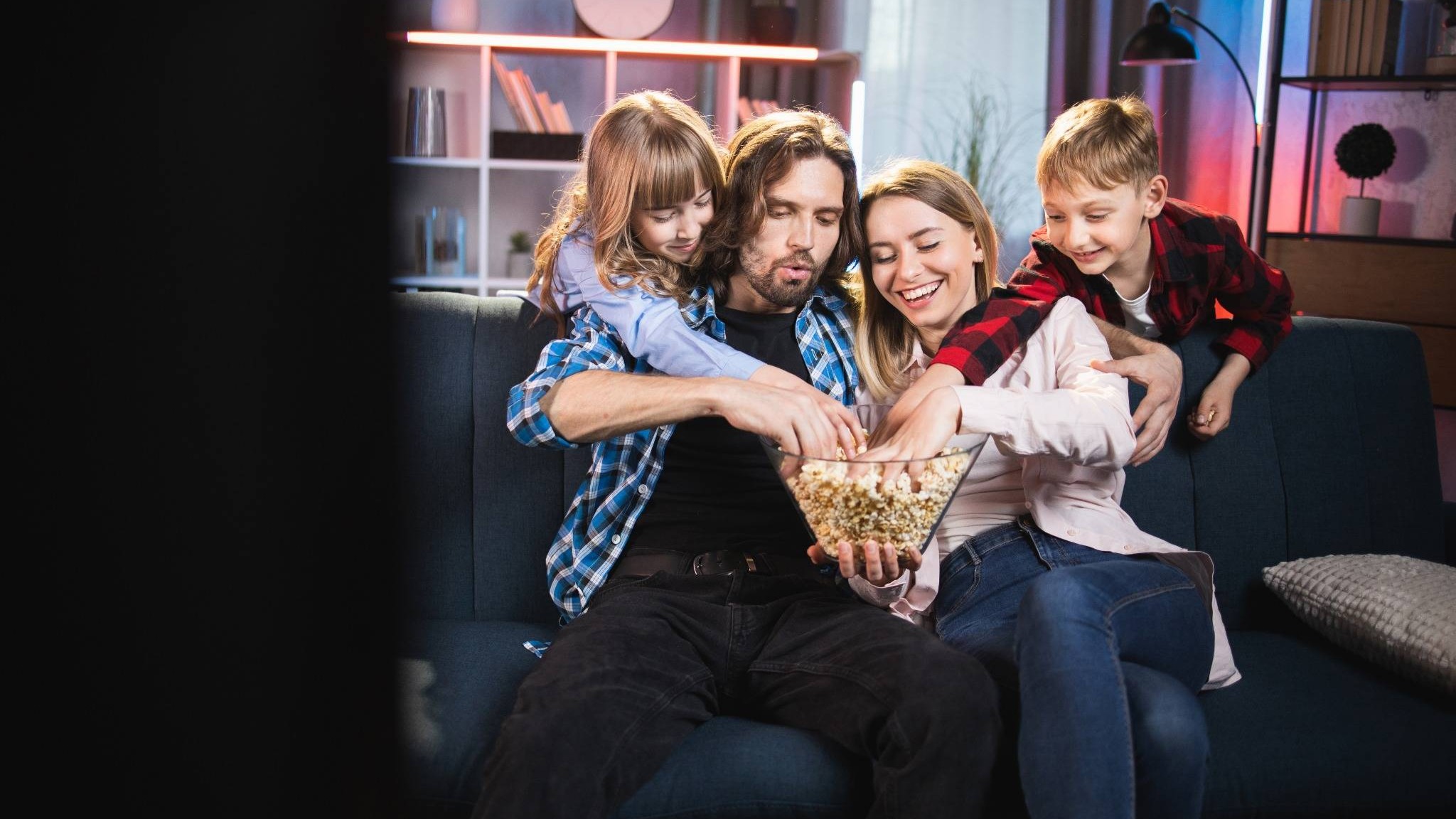 Family enjoying movies together, relaxed and smiling.