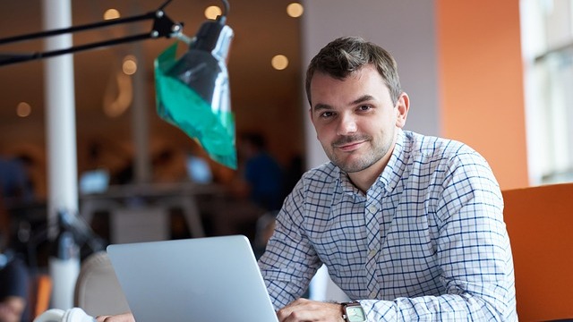 Young man sitting on a sofa with movie posters in the background, employer branding feel.