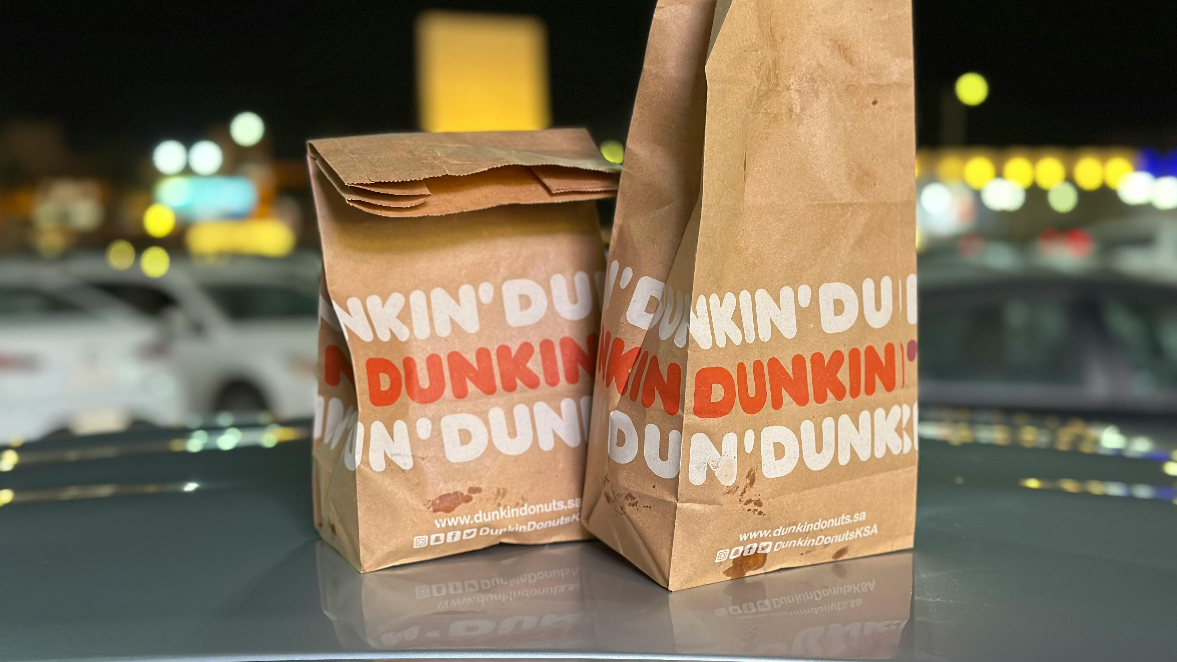 Dunkin' storefront window with latte sign and open message.
