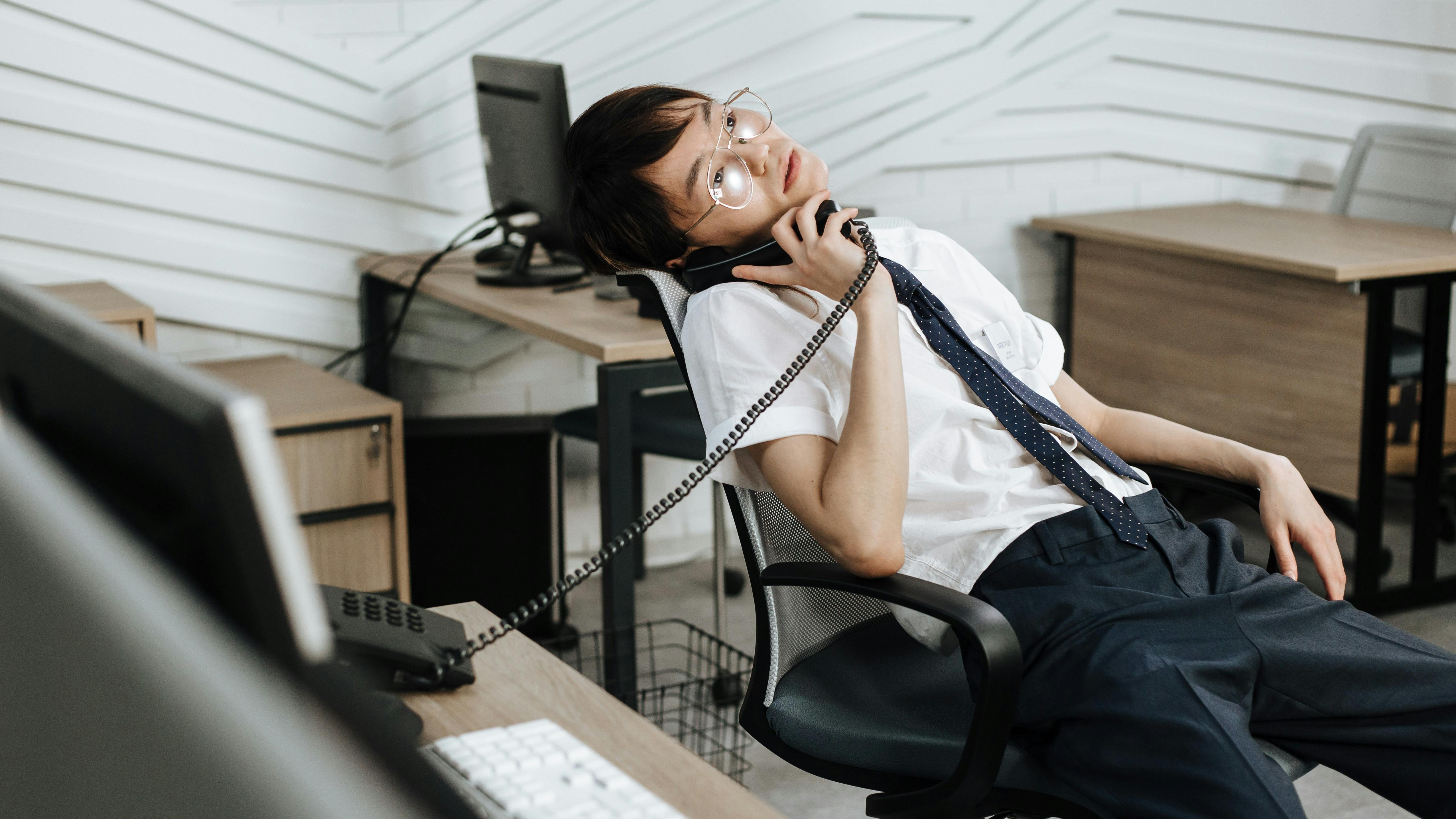 Bored young man in office holding clock, showing importance of workplace culture.