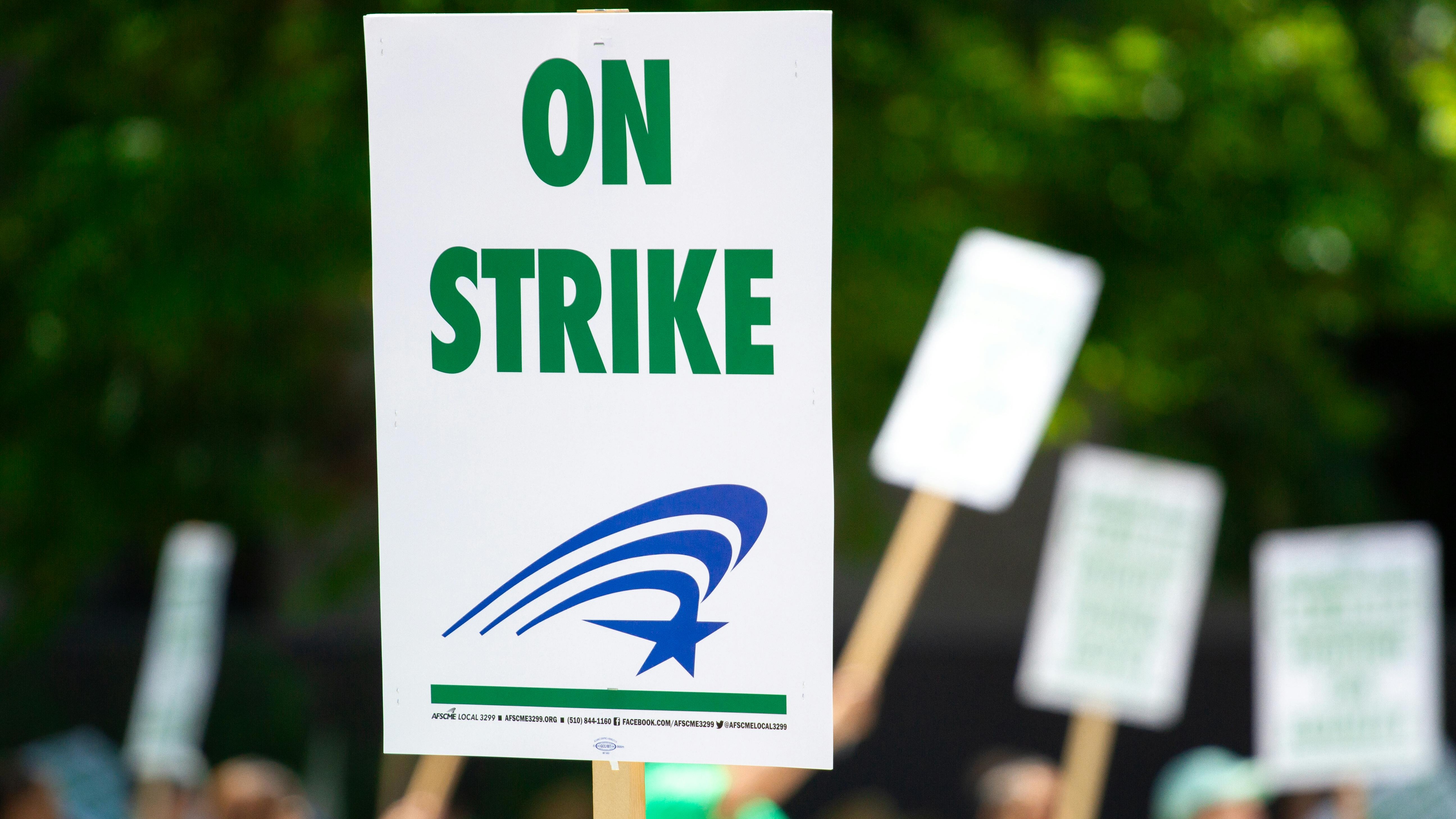 Hands holding 'STRIKE' sign, representing Bronx Defenders strike deal.