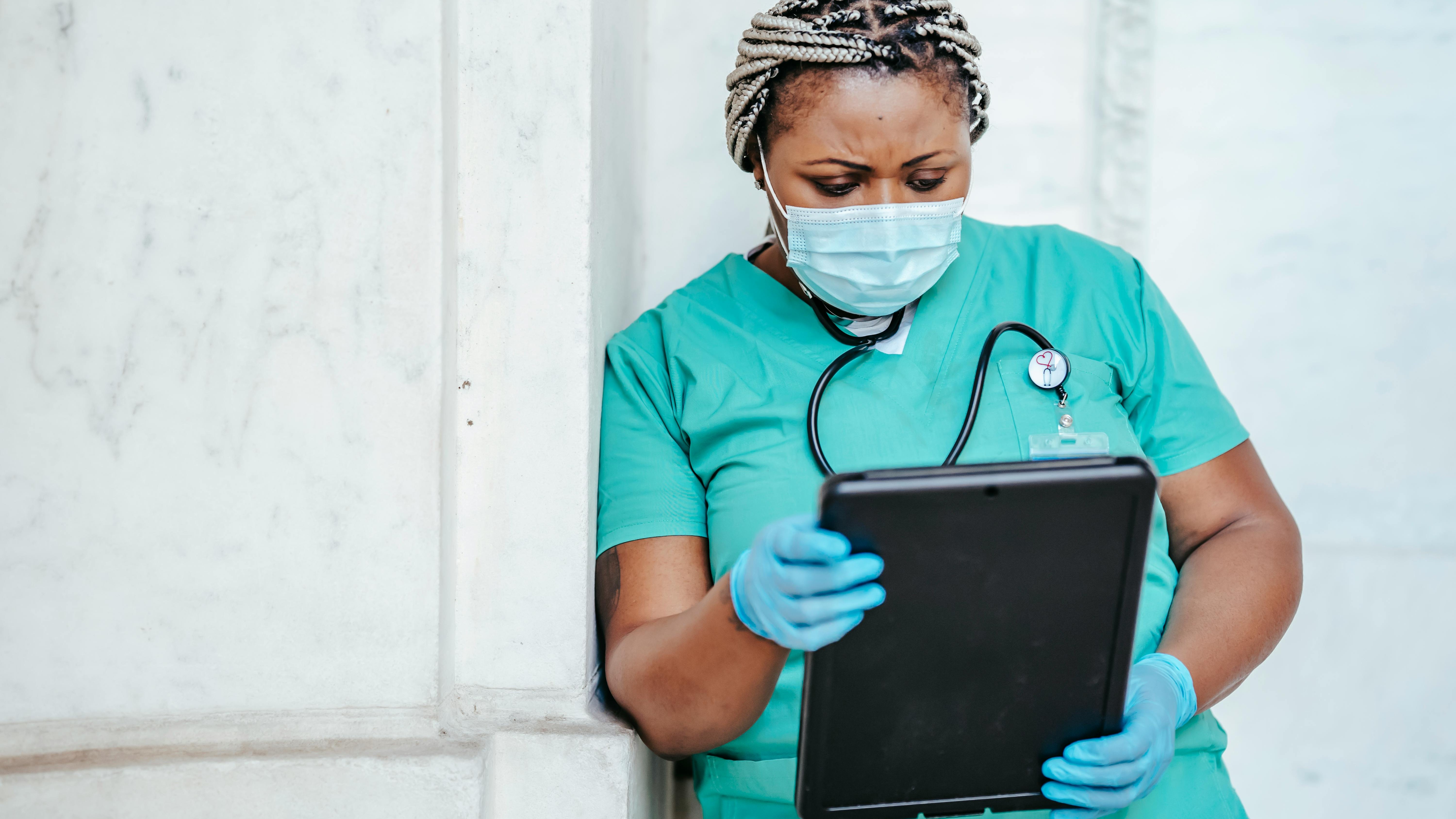 Tired nurse in corridor reflecting on salary trends.