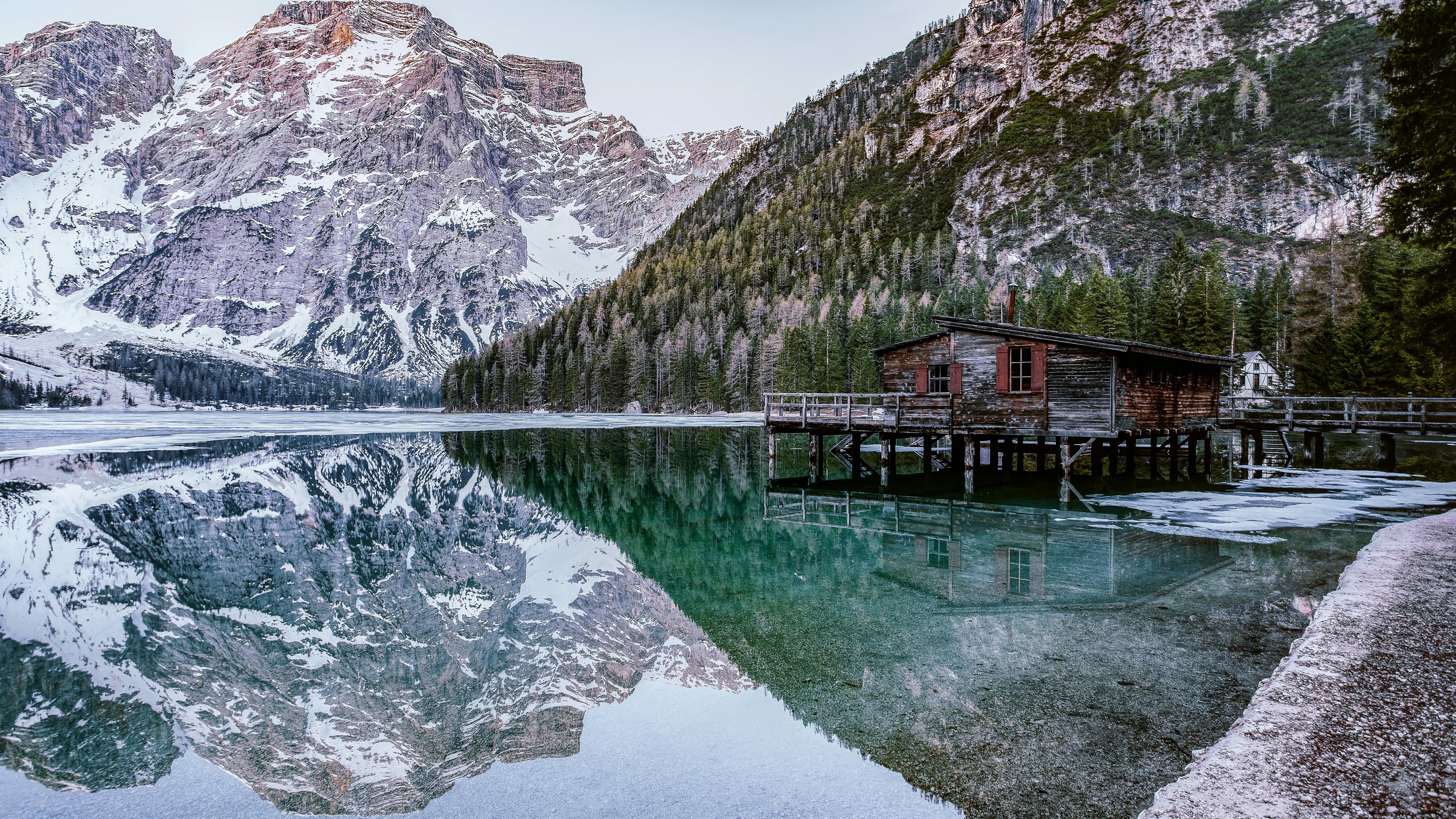 Rustic boathouse by Lago di Braies with mountain backdrop.