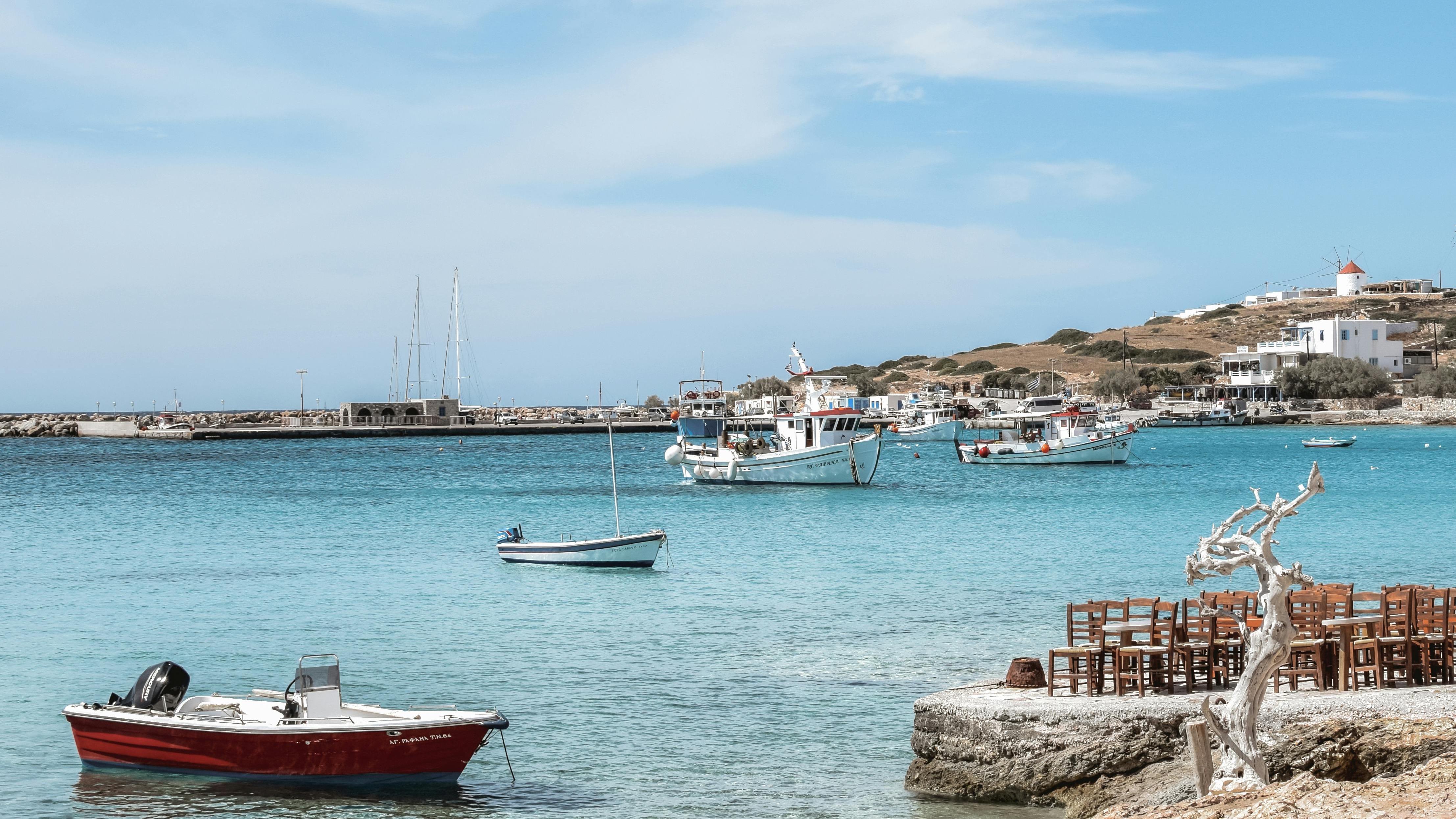 Most Beautiful Greek Islands: Vibrant coastal village with colorful houses by turquoise sea.