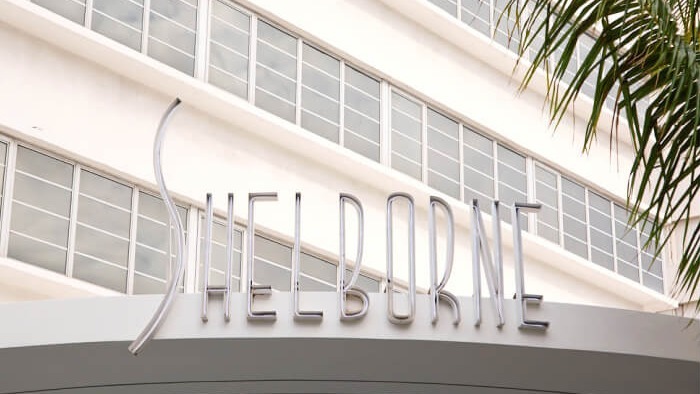 Miami Beach hotel renovation sign with palm tree and blue sky.