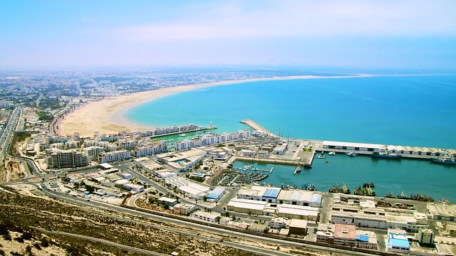 Scenic view of Agadir's coast at sunset with colorful buildings.
