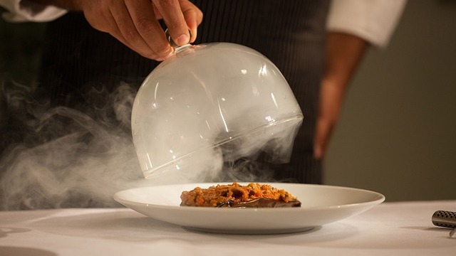 Top Michelin star chef delicately tasting dish in kitchen